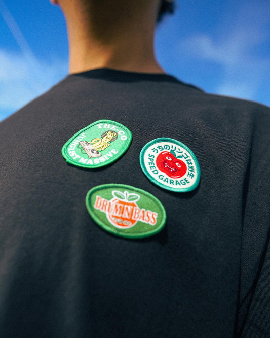 Person wearing three patches on a dark shirt with a blue sky background